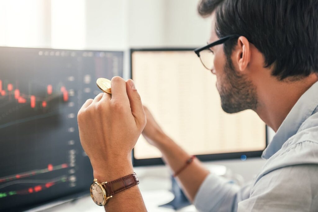 Man Looking At Charts On Screen While Holding Gold Bitcoin Wfivptk.jpg