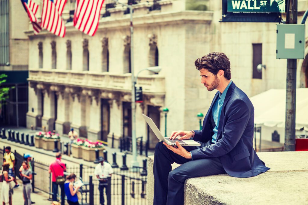 Trader with laptop on wall street.jpg