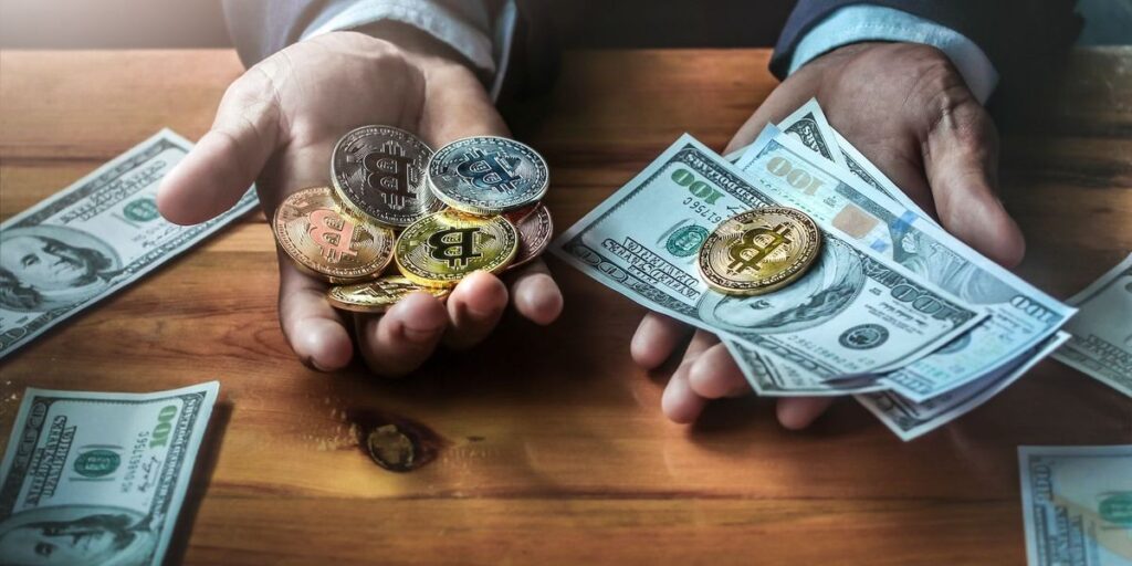 Hands holding bitcoin coins and us dollar bills on a wooden table.jpg